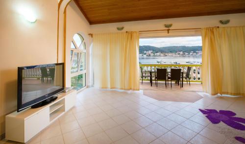 a living room with a large television and a balcony at Apartments Slavko in Supetarska Draga