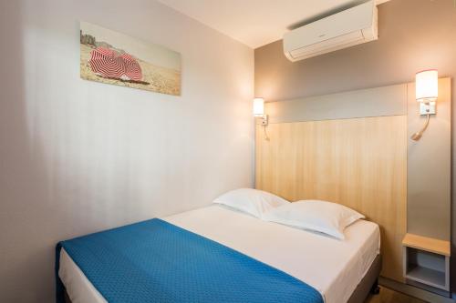 Dormitorio pequeño con cama con manta azul en Résidence Pierre & Vacances l'Ange Gardien en Villefranche-sur-Mer