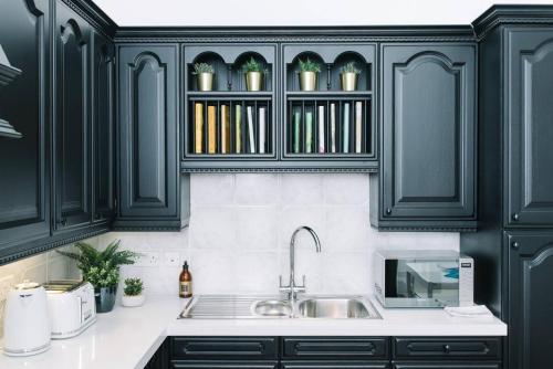 a kitchen with black cabinets and a sink at ALTIDO Palmerston Place Residence - Luxury City Centre Apt with Private Parking in Edinburgh