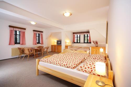 イレムニツェにあるRestaurace a penzion Jilmのベッドルーム1室(ベッド2台、テーブル、椅子付)