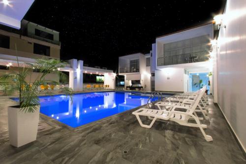 una piscina con sillas blancas junto a un edificio en Cumbaza Hotel & Convenciones en Tarapoto