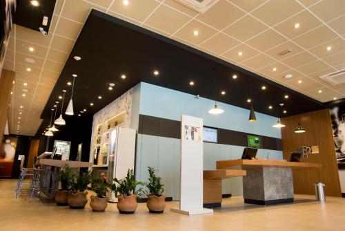 a lobby with a counter and potted plants at ibis Aracruz in Aracruz