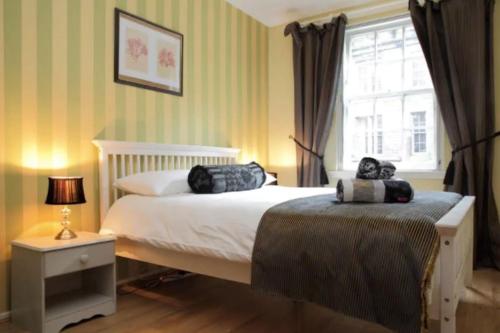 um quarto com uma cama e uma janela em JOIVY Stylish Castle View Apartment em Edimburgo