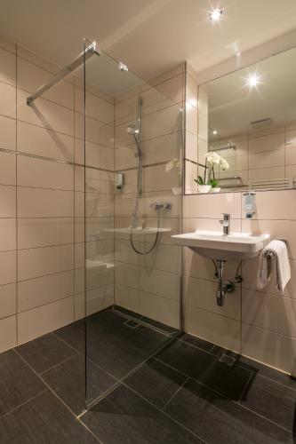 a bathroom with a glass shower and a sink at Hotel am Krone Park in Olching