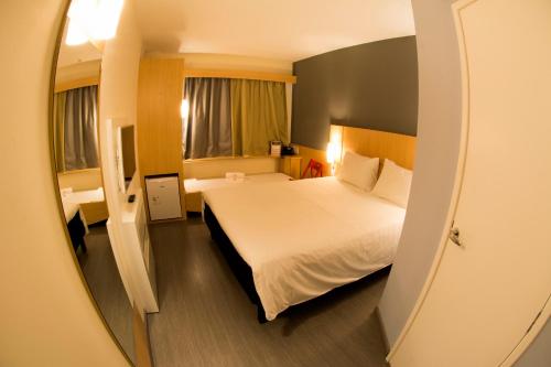um quarto de hotel com uma cama e um espelho em ibis Aracruz em Aracruz