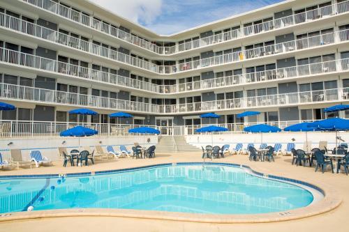 uma piscina em frente a um hotel com cadeiras e guarda-sóis em Sea Club IV Resort em Daytona Beach Shores