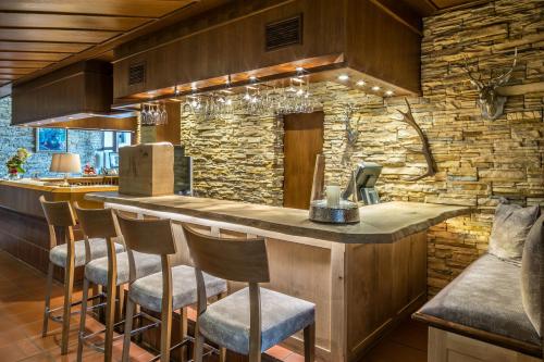 a kitchen with a bar with chairs and a stone wall at Hotel am Krone Park in Olching