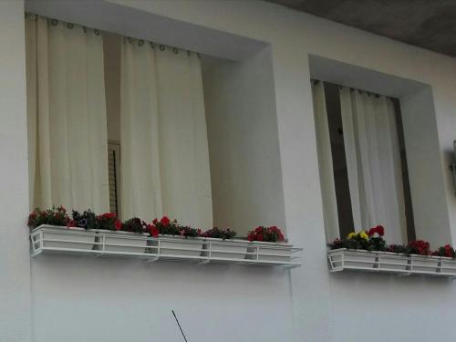 Deux boîtes de fenêtre avec des fleurs sur elles, dans un bâtiment dans l'établissement Case Vacanze di Isabella Stoia, à Giardini Naxos