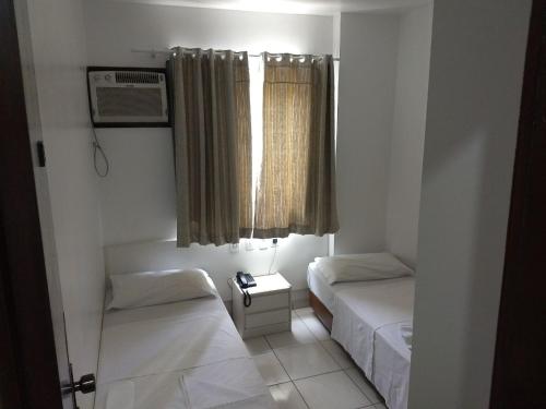 Habitación pequeña con 2 camas y ventana en Master Hotel, en Balneário Camboriú