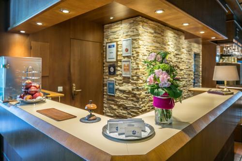 a lobby with a counter with flowers in a vase at Hotel am Krone Park in Olching