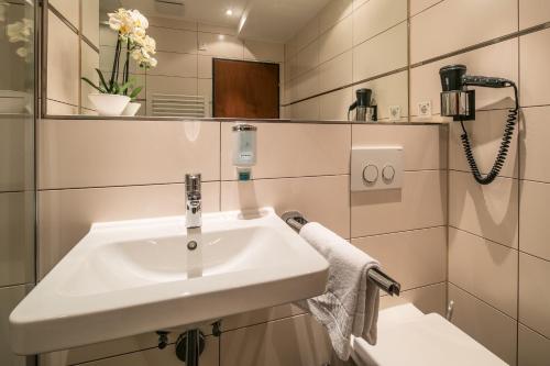 a bathroom with a white sink and a mirror at Hotel am Krone Park in Olching