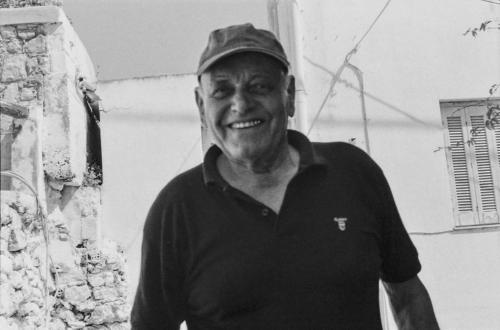 a man wearing a hat standing next to a building at Angelos Design Suites in Patitiri