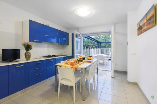 una cocina con armarios azules y una mesa con sillas en Villa Lucchese, en Lignano Sabbiadoro