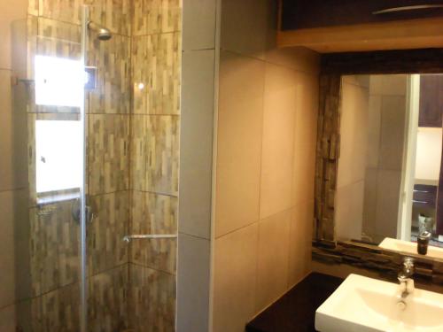 La salle de bains est pourvue d'une douche, d'un lavabo et d'un miroir. dans l'établissement Forest Cove cottage, à Knysna