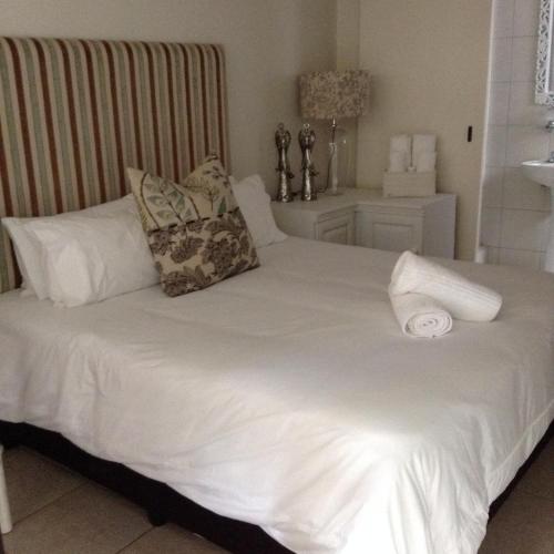 Una cama blanca con 2 almohadas y una toalla. en Broadway, en Durban