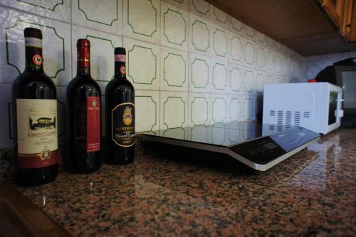 three bottles of wine sitting on a counter with a laptop at Casa Fonte di Bacco in San Miniato