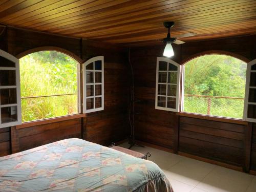 a bedroom with two windows and a bed in it at Floresta Tropical in Barra de Guaratiba
