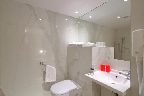 a bathroom with a toilet and a sink and a mirror at Hôtel Hor Les Lumières in Paris