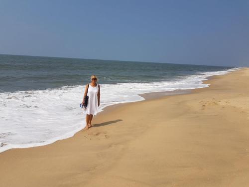 a woman in a white dress standing on the beach at Marari Nadiya in Mararikulam