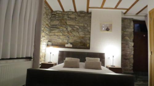 a bedroom with a bed and a stone wall at B&B Nord Sud in Salmchâteau