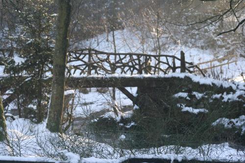 a wooden bridge in a snow covered forest at Les Chanterelles in Jalhay
