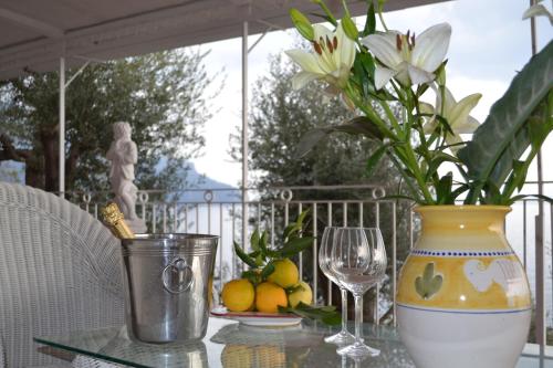 a vase with flowers sitting on a table with a glass at Villa Petit Ludovica in Ravello
