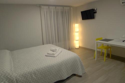 1 dormitorio con cama blanca, mesa y escritorio en Alojamientos Templete, en Caravaca de la Cruz