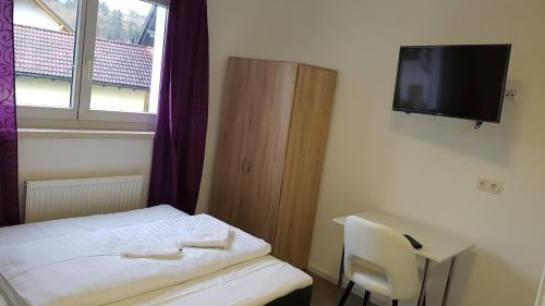 a small room with a bed and a tv on the wall at Gasthaus Sofram in Frastanz