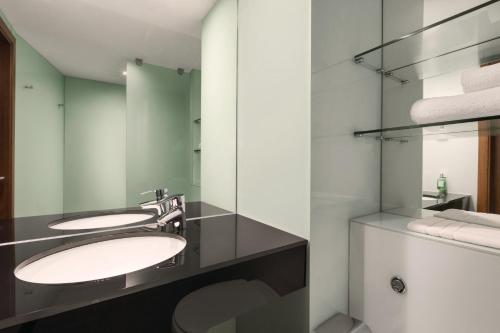 a bathroom with two sinks and a mirror at Ramada Encore Leicester City Centre in Leicester