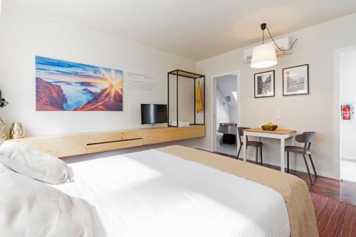 - une chambre avec un grand lit blanc et une table dans l'établissement Downtown Funchal Apartments by An Island Apart, à Funchal