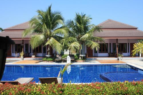 a resort with a swimming pool and palm trees at Waterside Resort in Pran Buri