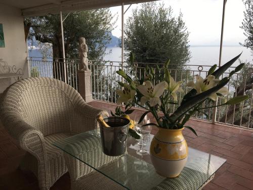 a glass table with a vase of flowers on a balcony at Villa Petit Ludovica in Ravello