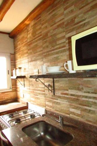 a kitchen with a sink and a television on a wall at Ñande Roga San Cemente in San Clemente del Tuyú