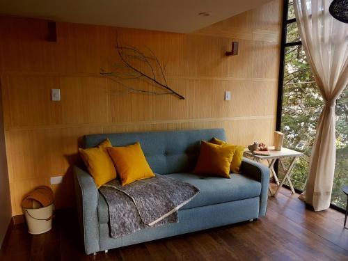 a blue couch with yellow pillows in a living room at La Quinta Glamping - Lago de Tota in Cuítiva