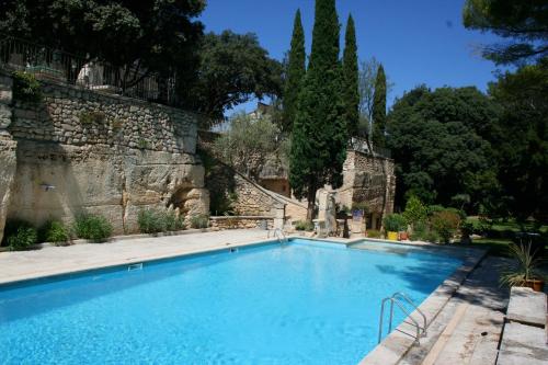 a swimming pool in front of a stone wall at Hôtel Belesso in Fontvieille