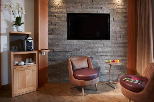a living room with a chair and a tv on a brick wall at Hotel Spa Restaurant Domaine du Moulin in Ensisheim