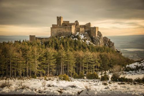 um castelo no topo de uma montanha na neve em Atardeceres d'Aragón em Fontellas