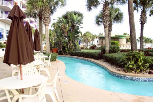 una piscina en el complejo con mesas y sombrillas en Ocean Walk Resort 603 en Daytona Beach