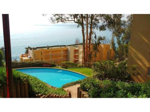 a swimming pool in front of a building and the ocean at Bahía Pelicanos Catalina in Ventanas