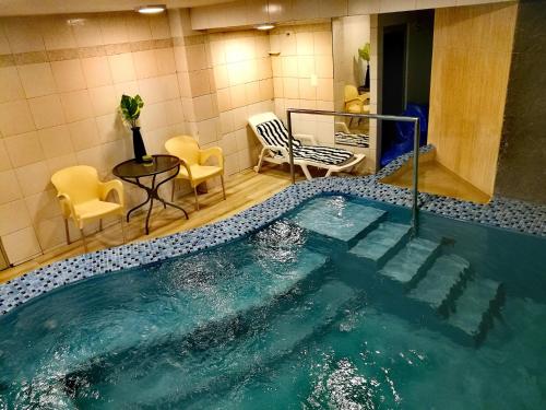 a pool of water in a room with chairs and a table at Alcalá Apart Hotel in La Paz