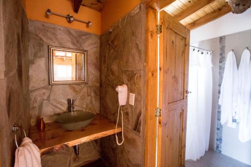 a bathroom with a sink and a stone wall at Cabañas del Espinillo in Villa General Belgrano
