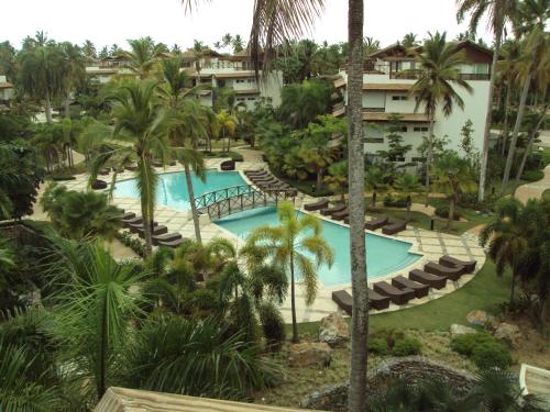 an aerial view of a resort pool with lounge chairs and palm trees at Xeliter Balcones del Atlantico - Las Terrenas in Las Terrenas