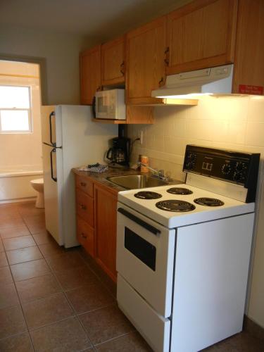 a kitchen with a white stove and a white refrigerator at SlumberLodge Hotel in Penticton