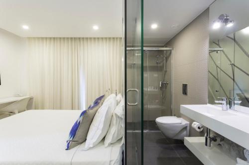 a bathroom with a bed and a shower and a toilet at Sport Hotel A Seleção in Setúbal