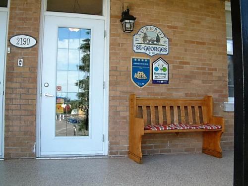 a wooden bench sitting in front of a brick building at Auberge le St-Georges in Saguenay