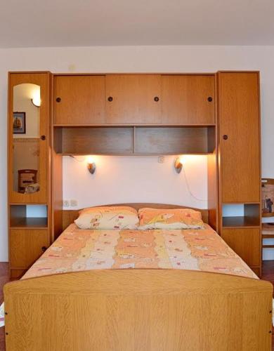 a bedroom with a bed with a wooden headboard at Apartmani Peko in Pag