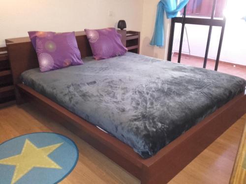 Cette chambre comprend un lit avec des oreillers violets et violets. dans l'établissement Albufeira INN - Casa do Parque - Elimar 5 T1, à Albufeira