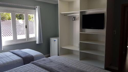 um quarto com uma cama, uma televisão e uma janela em Casa de Oliveira Pousada em Torres