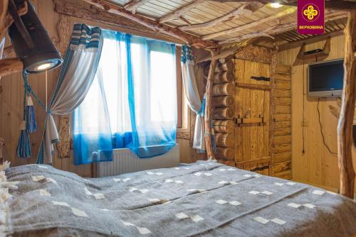 a bedroom with a bed with a blue blanket and a window at Плай in Verkhovyna