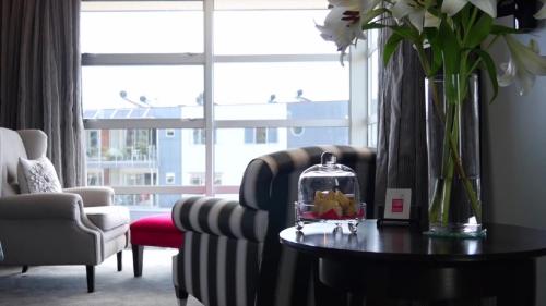 a living room with a chair and a table with flowers at Top Floor Bed and Breakfast in Paraparaumu Beach